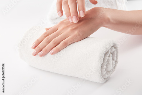 Partial view of female hands on terry towel on white background