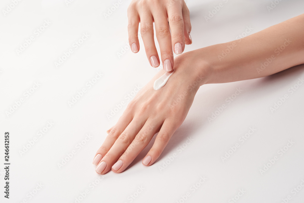 Partial view of woman applying cosmetic cream on white background Partial view of woman applying cosmetic cream on white background