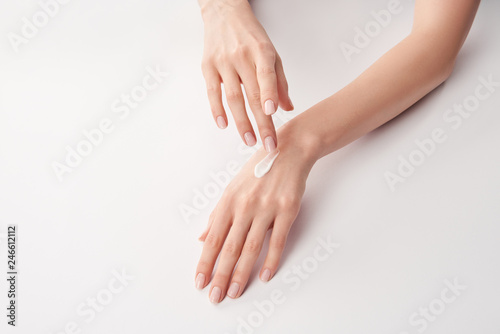 Partial view of woman applying cosmetic cream on white background photo