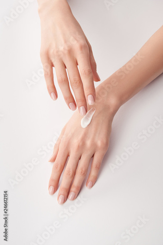 Partial view of woman applying cosmetic cream on white background photo