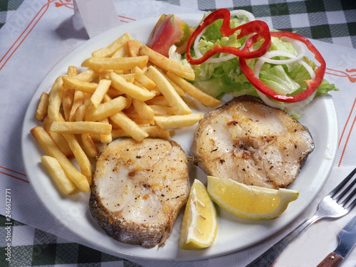 Plato de merluza a la plancha con patatas fritas y ensalada.