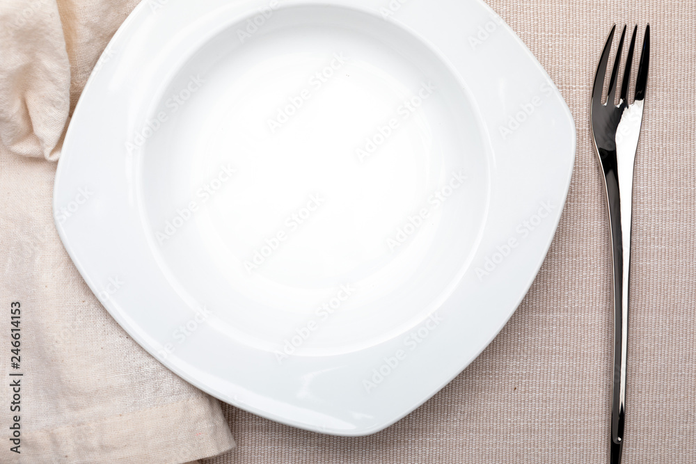 Empty white plate. On delicate beige tablecloth. Concept to include your food and your text. Empty white plate. On delicate beige tablecloth. Concept to include your food and your text.