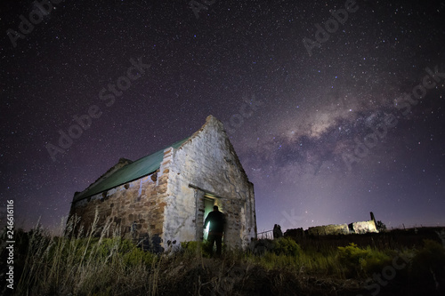 Wide angle astrophotography scene of an old abandoned building with the bright nigh sky above it. photo