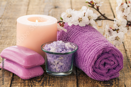 Soap, sea salt in glass bowl with towel for bathroom procedures and burning candle with flowering branch of apricot tree