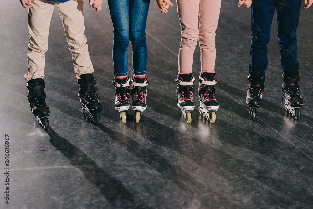 Partial view of children in roller skates standing in roller rink and holding hands Partial view of children in roller skates standing in roller rink and holding hands