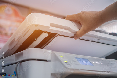 Business office Concept : Hand person employed press button on panel of printer for process paperwork on laser print cartridge, lay down or take papers from laser office copy machine at Busy Offices.