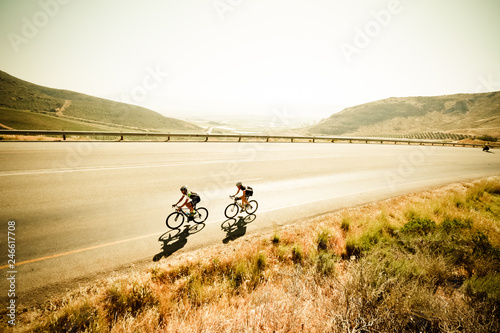 Wide angle view of a road cyclist riding on a tarmac road in the country side with a great view over the farmlands of the western cape in south africa