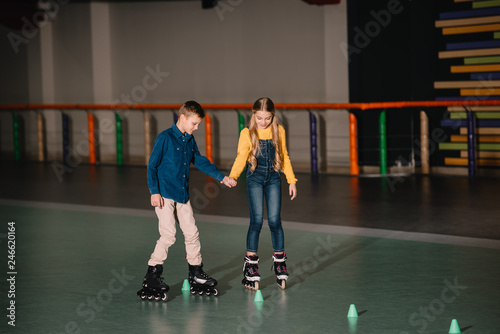 Two children practicing scating on rollers with holding hands