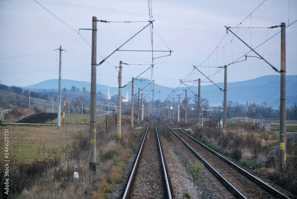 Eastern European railroad across Transilvania. Mountain landscape in the background. Scary, dangerous scene in winter with naked trees and polluted nature Eastern European railroad across Transilvania. Mountain landscape in the background. Scary, dangerous scene in winter with naked trees and polluted nature
