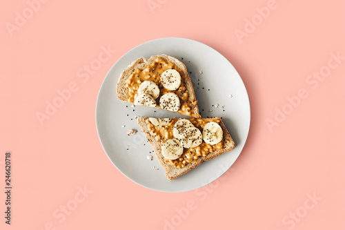 Peanut butter chia seed banana toast for breakfast on a pink background, healthy snack, top view