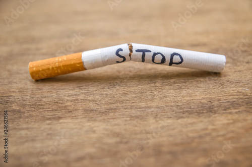 broken cigarette with the word stop on a wooden background; stop smoking close up concept