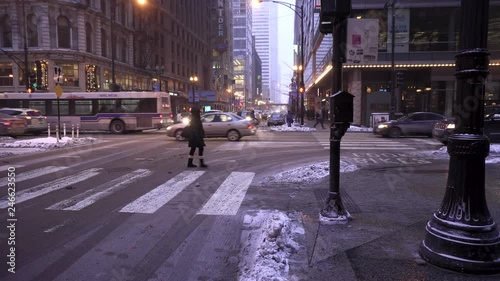 pedestrians brave the Chicago winter sub-zero temperature downtown at dusk.