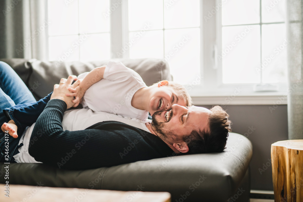 A Portrait of handsome father and his cute son having fun on sofa at home
