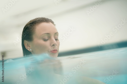 Portrait of elegant young woman in swimming pool with red lipstick