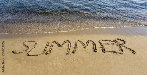 Summer word written / handwritten in sand on wet sandy beach. New summer is coming and holiday vacation travel time concept. I love summer and need holiday message on coast. Copy space for ad banner.