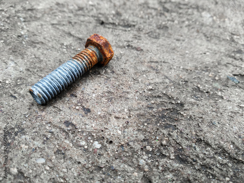 Rusty bolt lying on the concrete ground, rustic bolt