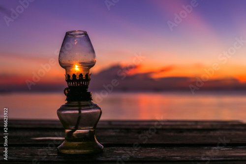 Beautiful old rustic oriental oil lamp silhouette in a beautiful amazing red velvet sunset sky at tropical island in Indian Ocean, Koh Phangan, popular tourist destination in Thailand.