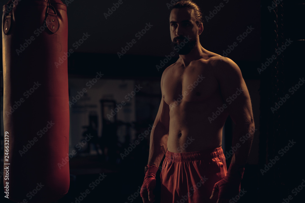 Fototapeta premium Bearded fighter standing by the heavy bag