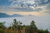 sunrise at Phu Thok, beautiful mountain view misty morning of top mountain around with sea of mist moving up to the sky with cloudy sky background, Chiang Khan District, Loei, Thailand.