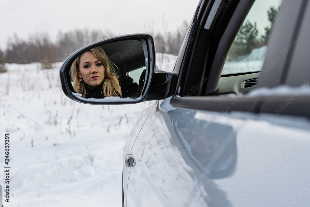 Blonde woman looking in the car rear-view mirror. Blonde woman looking in the car rear-view mirror.