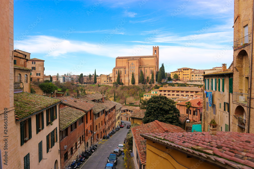 Amazing view to Basilica Cateriniana di San Domenico with old medieval houses and street in Siena, Tuscany, Italy under a blue high winter sky