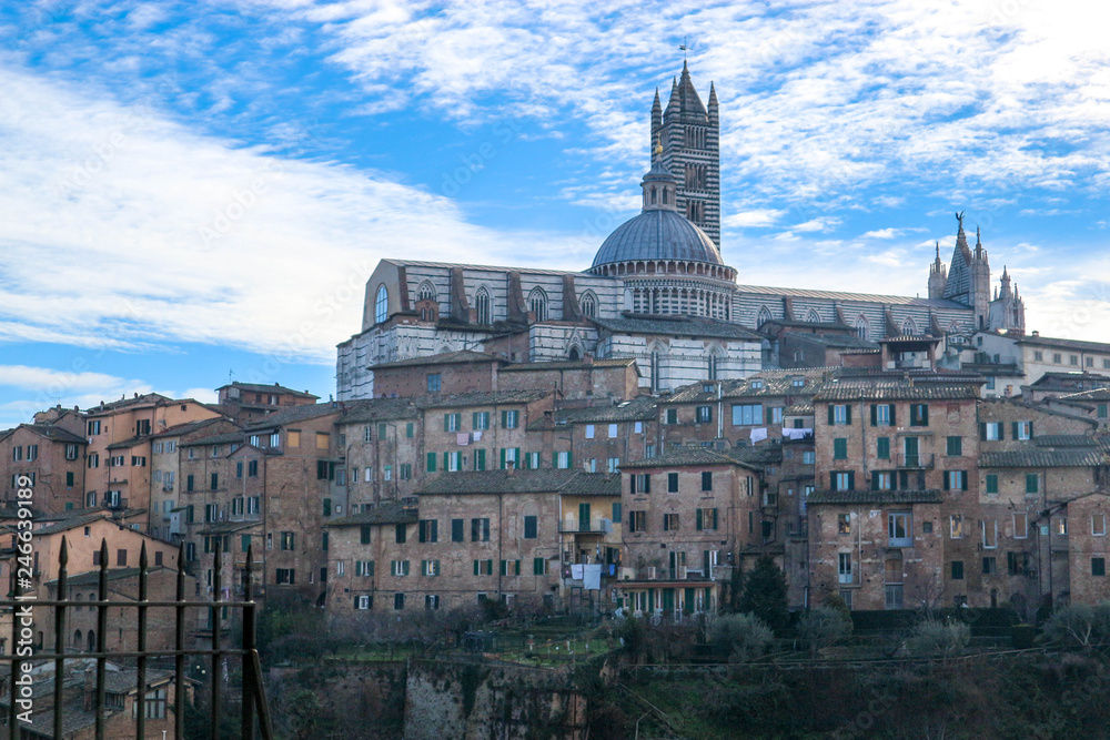 Panoramic view of Siena old town and cathedral with bell tower in winter morning with blue sky and clouds on the background, Tuscany, Italy