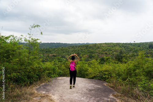 Asian woman with pink backpack standing on rock cliff