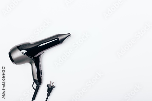 Top view hair dryer on white background, copy space. Minimal flat lay arrangement of electrical appliance for hair styling.