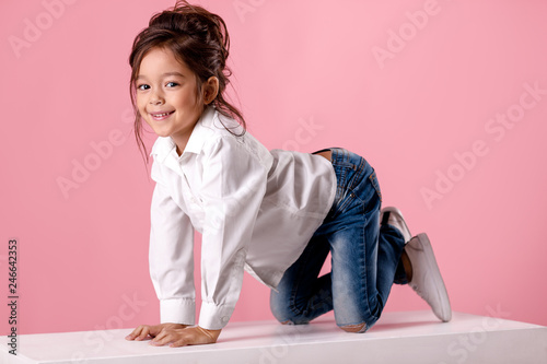 smiling little girl in white shirt with hairstyle looking to camera