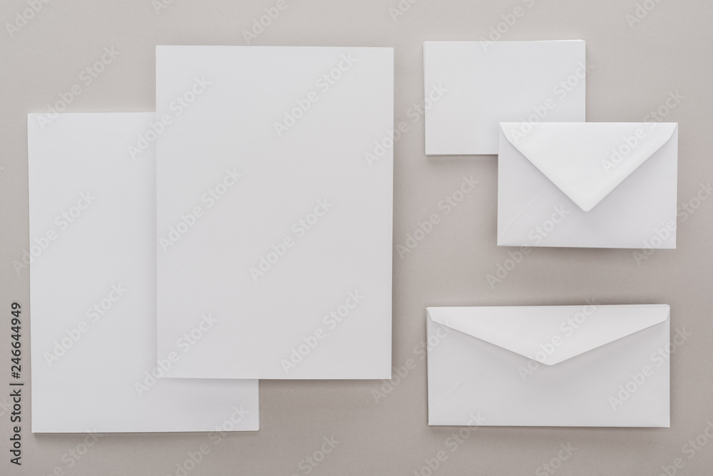 flat lay with white blank papers and envelopes on grey background flat lay with white blank papers and envelopes on grey background