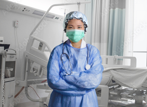 confident and successful Asian Korean medicine doctor woman in hospital scrubs and mask posing isolated at clinic patient bed in medical health care as corporate physician