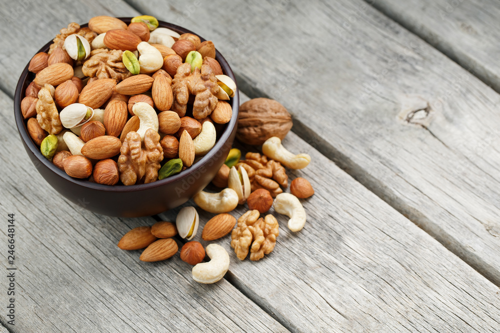 Wooden bowl with mixed nuts on a wooden gray background. Walnut, pistachios, almonds, hazelnuts and cashews, walnut. Wooden bowl with mixed nuts on a wooden gray background. Walnut, pistachios, almonds, hazelnuts and cashews, walnut.