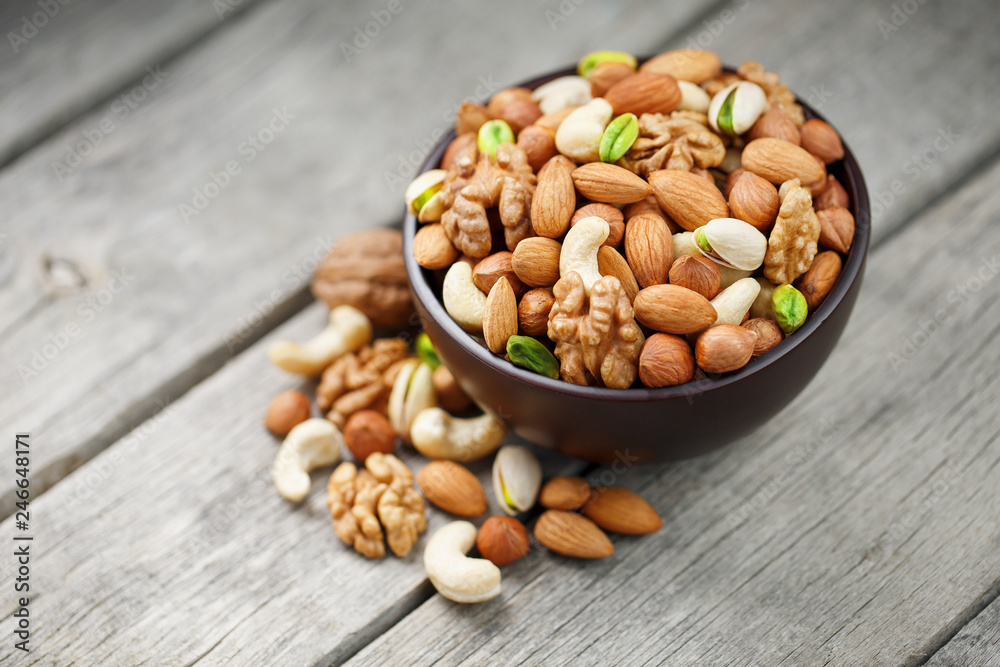 Wooden bowl with mixed nuts on a wooden gray background. Walnut, pistachios, almonds, hazelnuts and cashews, walnut. Wooden bowl with mixed nuts on a wooden gray background. Walnut, pistachios, almonds, hazelnuts and cashews, walnut.