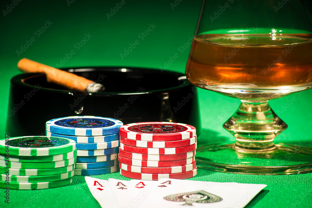 The concept of gambling, cards and chips with a glass of cognac and a cigar The concept of gambling, cards and chips with a glass of cognac and a cigar