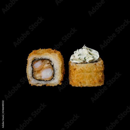 Sushi. Baked roll with tempura shrimp, cream cheese and herbs, isolated in black background