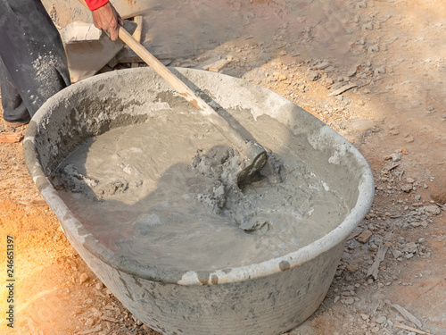 Mixing concrete by hands and spade in black basin
