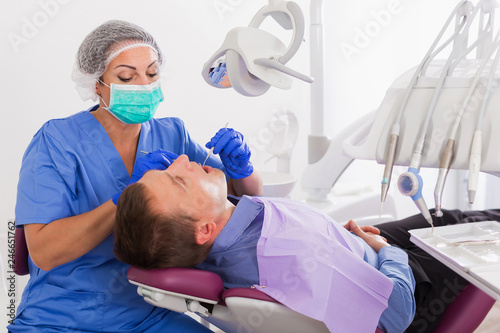 adult dentist checking teeth of patient
