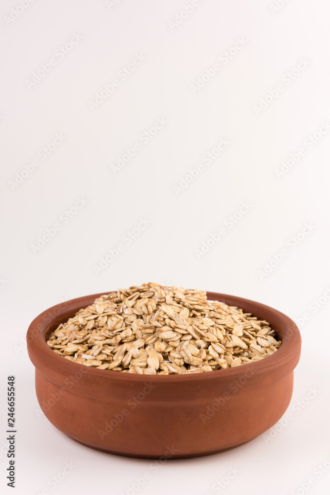 Dry rolled oatmeal in bowl isolated on white background.