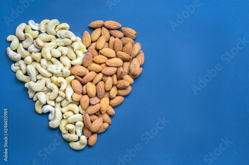 Heart made from almond and cashew isolated on blue background. top view.
