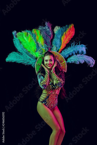 Beautiful young woman in carnival peacock costume. Beauty model woman at party over holiday background with magic glow. Christmas and New Year celebration. Glamour lady with perfect make up and