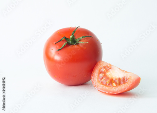 A whole red tomato and a slice