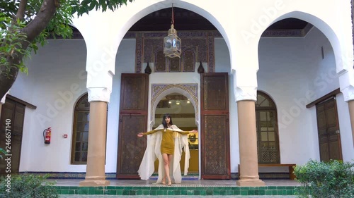 Beautiful Moroccan Girl Waving her white mantle in Picturesque Dar Si Said Riyad in Marrakech at sunset time photo