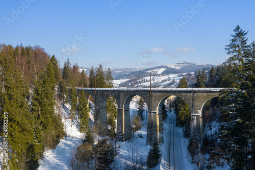 Fototapeta Naklejka Na Ścianę i Meble -  Winter scenery in Silesian Beskids mountains. Railwai viaduct in Wisla Glebce. Aerial view from above. Landscape photo captured with drone. Poland, Europe.