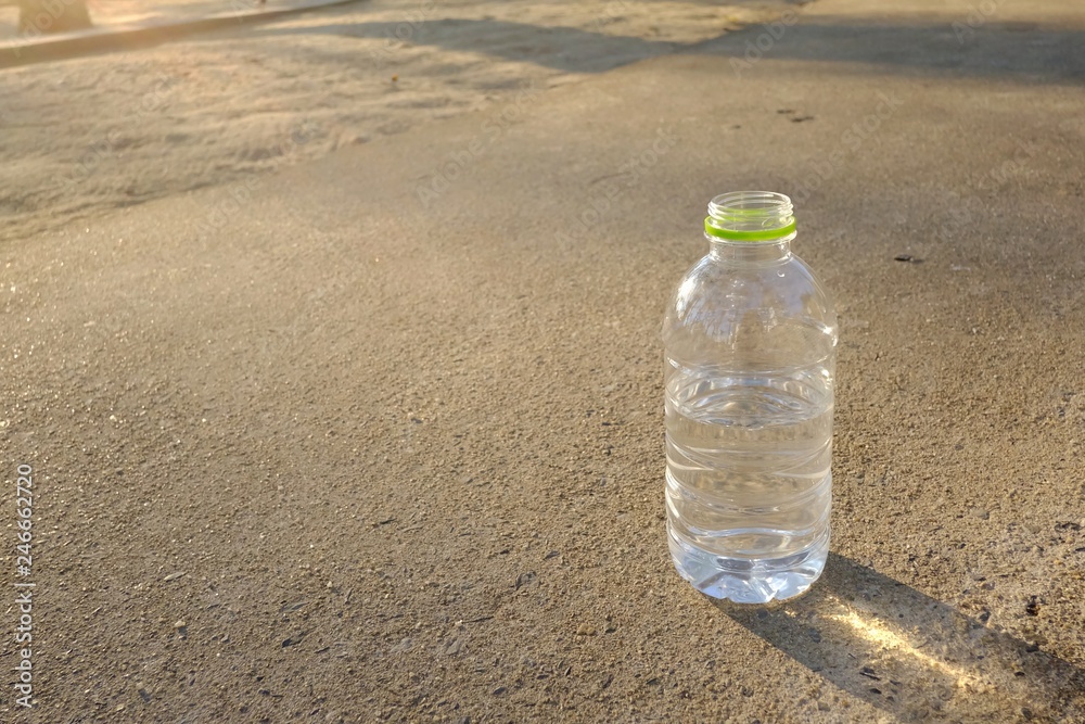 A plastic bottle of drinking water on the road way at the park with silhouette sunlight and shadow A plastic bottle of drinking water on the road way at the park with silhouette sunlight and shadow