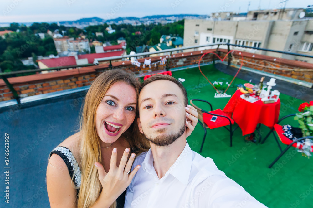 selfie couple in love. girl hugs guy and shows engagement ring o