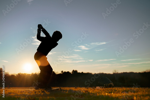 Young junior golfer practicing in a driving range with beautiful sunset light in winter. photo
