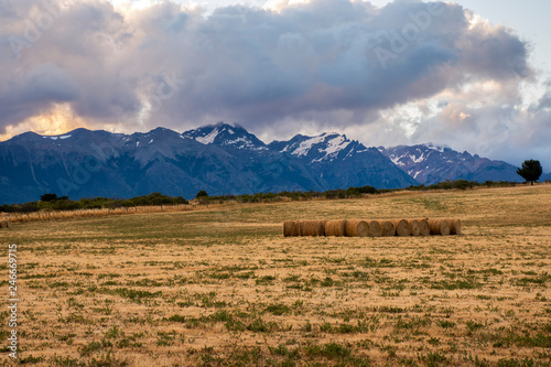 round bales of straw in a Patagonia field against Andes mountains.