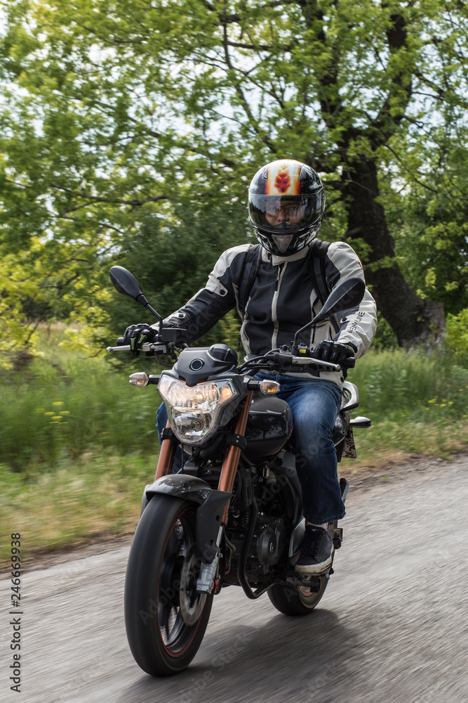 The biker in action or movement riding around a curve road. Speed of inspiration and wild energy on the road. Get faster. Biker is driving the handsome sport motorbike near meadows on country side The biker in action or movement riding around a curve road. Speed of inspiration and wild energy on the road. Get faster. Biker is driving the handsome sport motorbike near meadows on country side