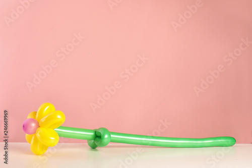 Flower figure made of modelling balloon on table against color background. Space for text