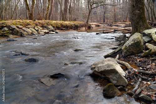 Water flowing around the rocks in a creek in the forest in winter, Potomac, Maryland, USA. Low shutter speed.